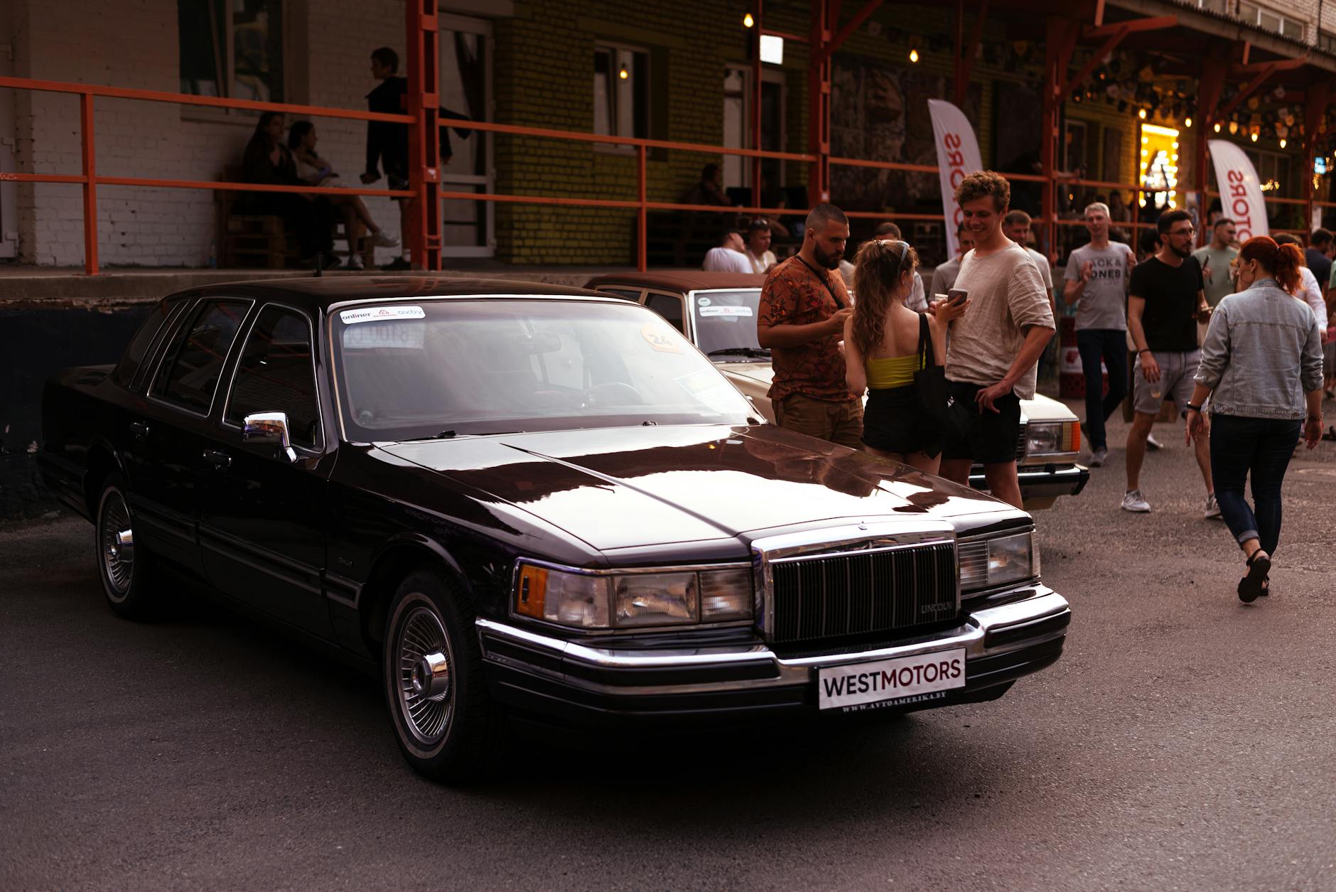 people standing beside a parked lincoln town car